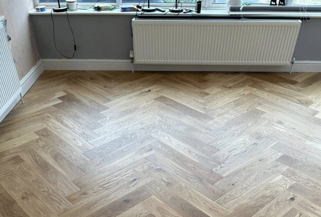 Natural oak herringbone parquet flooring beside a white radiator in bright room