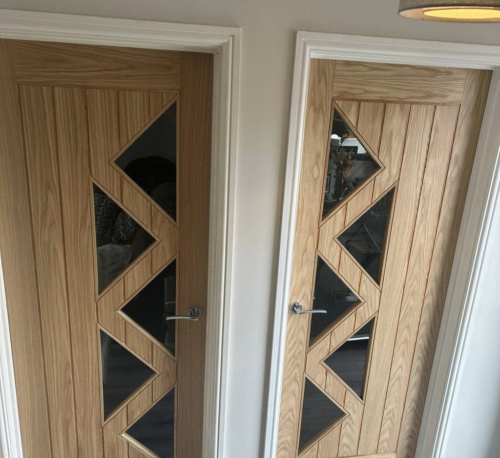 Two oak interior doors with bold zigzag cut-out glass panels and chrome handles