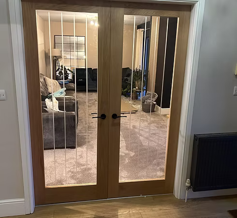 White uPVC French doors opening onto a wet timber deck against a red brick exterior wall